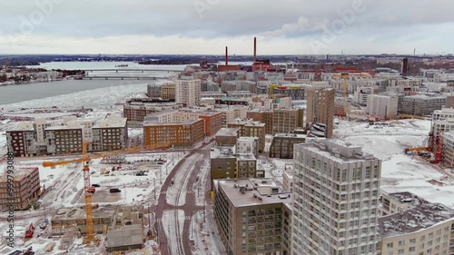 Helsinki.Finland-February 3.2022: Drone shot of a new residential area next to West terminal called Jatkasaari. Cloudy sky. Ongoing construction. Camera moving backwards while zooming out. photo