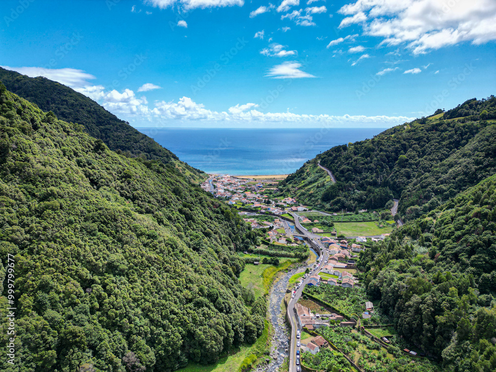 Aerial drone view of the small picturesque town Faial da Terra. Green valley, river, mountains, beautiful coastline and blue water of the Atlantic Ocean. Sao Miguel Island, Azores, Portugal Aerial drone view of the small picturesque town Faial da Terra. Green valley, river, mountains, beautiful coastline and blue water of the Atlantic Ocean. Sao Miguel Island, Azores, Portugal
