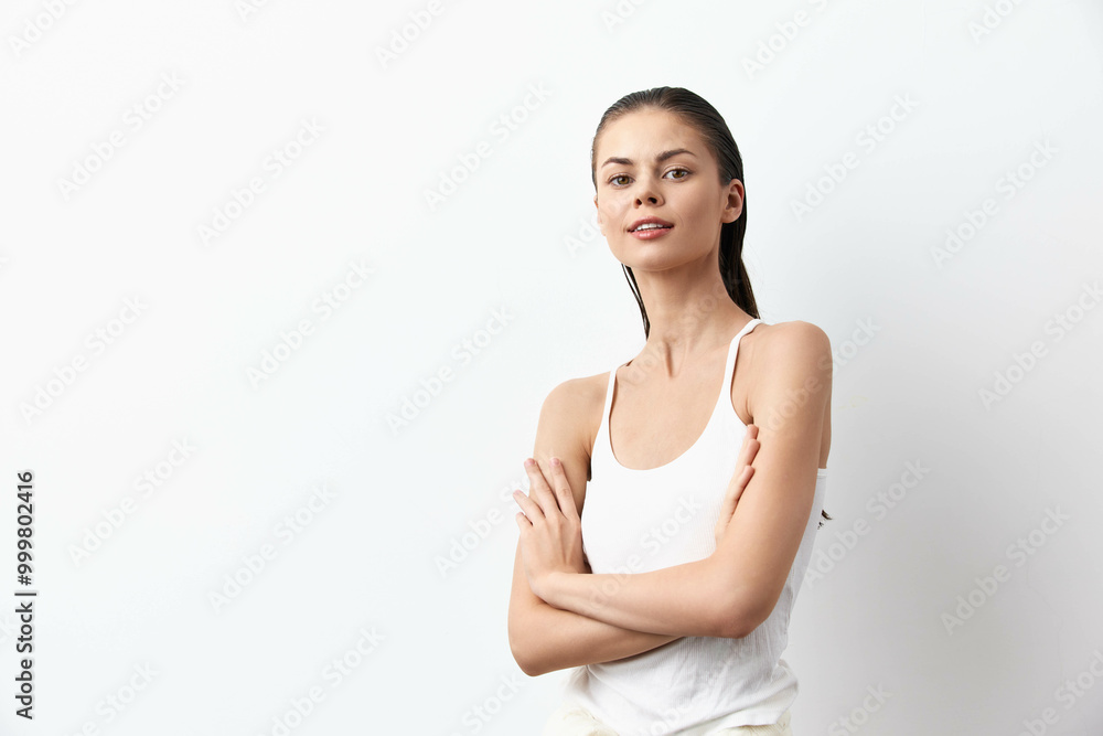 Portrait of a confident young woman with crossed arms, casually dressed in a tank top, standing against a clean white background, projecting self assuredness and serenity Portrait of a confident young woman with crossed arms, casually dressed in a tank top, standing against a clean white background, projecting self assuredness and serenity