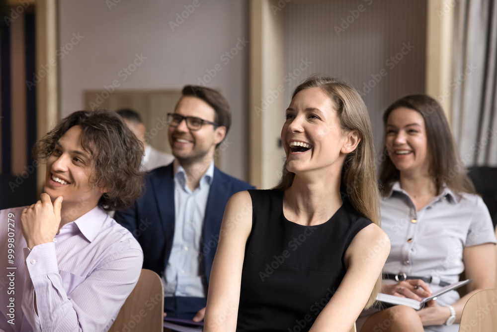 Joyful group of employees having fun at conference meeting, sitting in lines, looking at speaker away, listening to presenter. Business team attending career training, educational seminar Joyful group of employees having fun at conference meeting, sitting in lines, looking at speaker away, listening to presenter. Business team attending career training, educational seminar