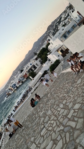 Mykonos, Greece - July 17, 2024: Tourists gather at Little Venice during sunset, enjoying the sea view and traditional white houses in one of Mykonos' most popular areas photo