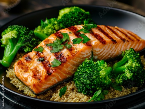 Grilled salmon served with broccoli and quinoa on a black plate.