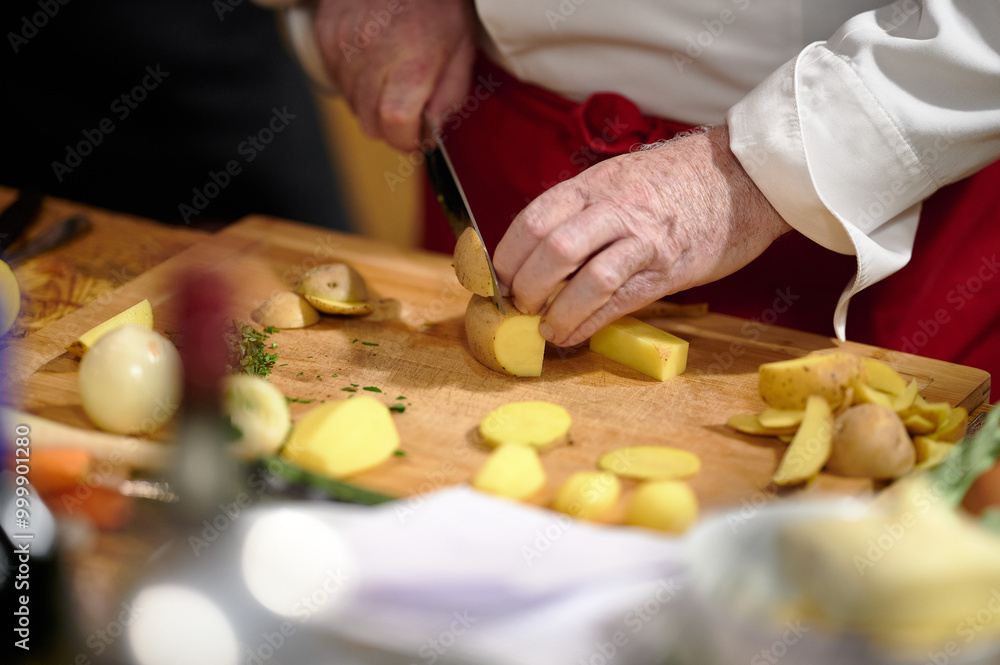 Chef Slicing Potatoes on a Wooden Cutting Board During Culinary Preparation in a Warm, Ambient Light Kitchen Setting