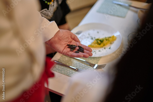 Obraz na płótnie Chef Presenting Exotic Seeds to Diners During a Tasting Experience in a Warm, Ambient Light Setting Over a Prepared Dish` w salonie