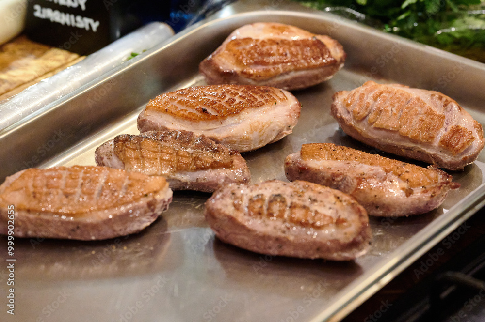 Golden-Brown Perfection: A Close-Up of Seared Meat Resting on a Tray in a Professional Kitchen Under Warm Ambient Lighting