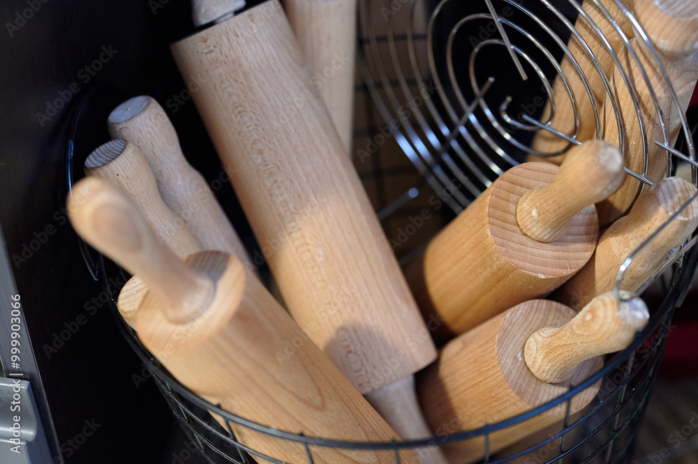Collection of Wooden Rolling Pins in a Metal Basket, Indoors, Captured in Soft Ambient Lighting