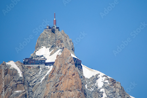 view from below of the station aiguille du midi on the mountain with a clear blue sky and sunshine photo