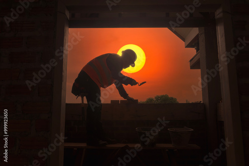 Silhouette of a bricklayer laying bricks at sunset, Thailand photo