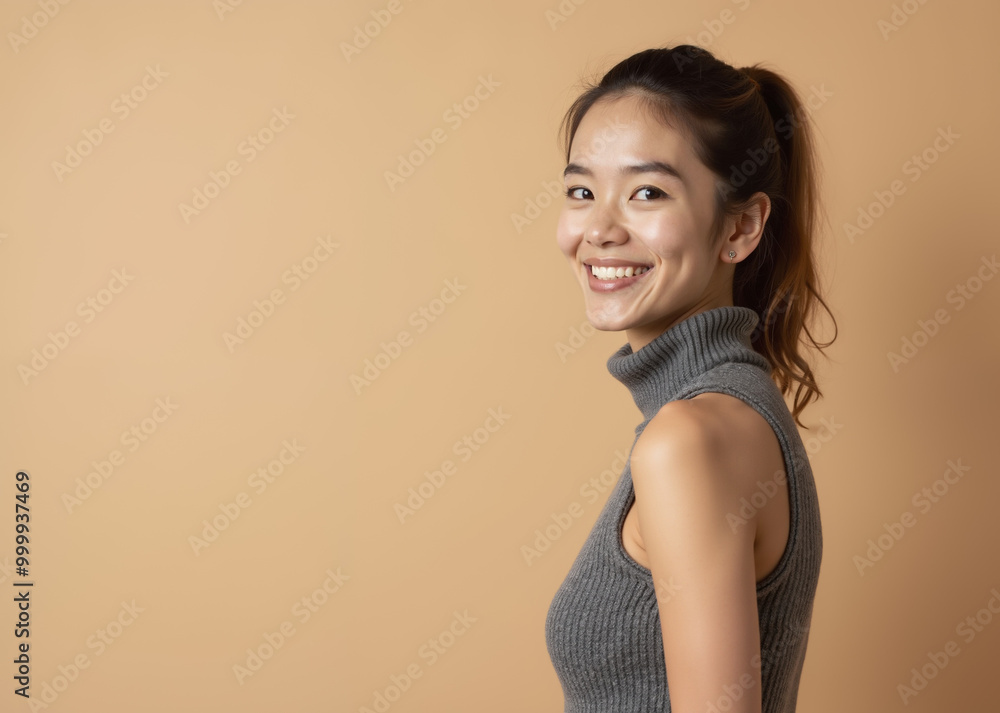 Asian woman with cheerful expression smiling against beige background with copy space Asian woman with cheerful expression smiling against beige background with copy space