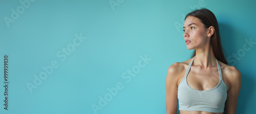 Young woman with thoughtful expression looking away against turquoise background with copy space photo