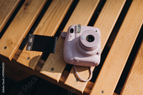 The pink camera on wooden background.