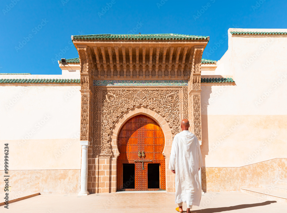 Φωτογραφία A Moroccan man wearing a white traditional outfit walks towards a mosque - Entrance of Mausoleum of Moulay Ismail in Meknes in Morocco