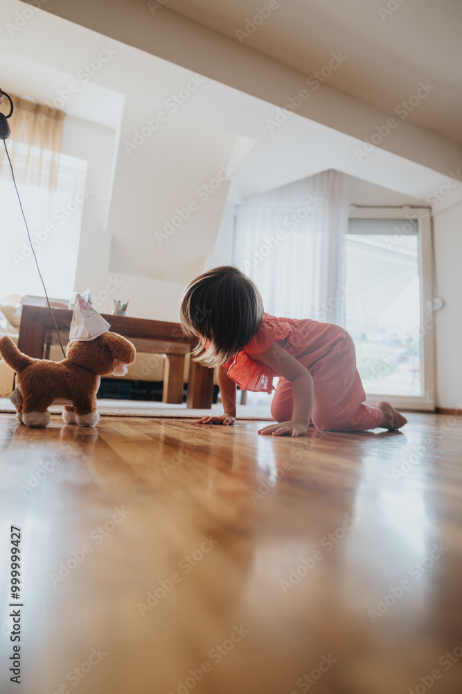 Φωτογραφία Young child engaging with a stuffed toy dog, playing happily on a hardwood floor in a bright, cozy living room