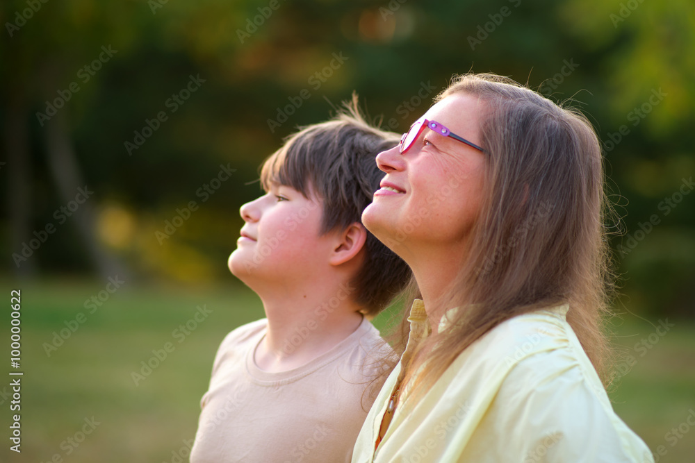 A joyful portrait of a woman and her teenage son enjoying a summer day together in the park. A happy family moment captured with a mother and her son smiling in the beauty of nature A joyful portrait of a woman and her teenage son enjoying a summer day together in the park. A happy family moment captured with a mother and her son smiling in the beauty of nature
