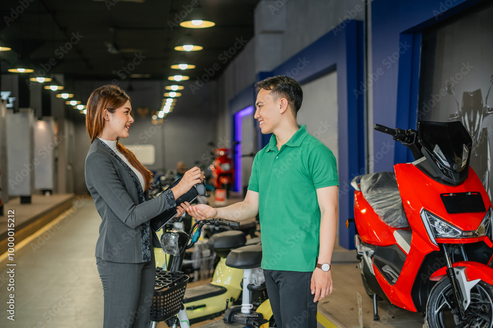 male customer receiving electric bicycle key from saleswoman male customer receiving electric bicycle key from saleswoman