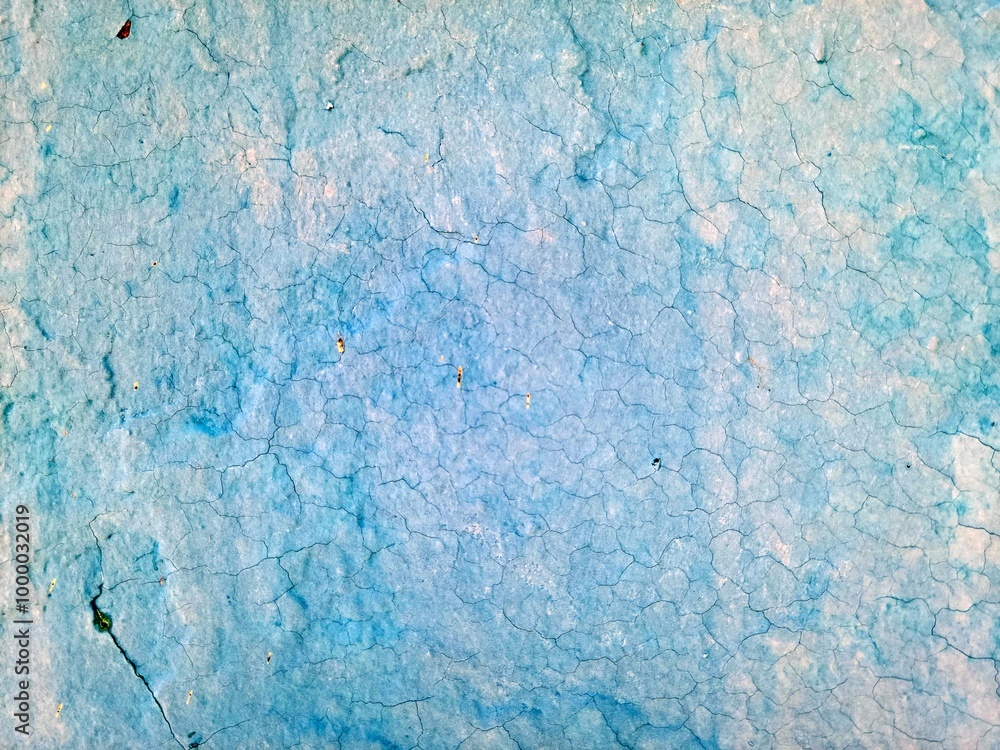Obraz premium A blue and teal surface features a cracked and weathered appearance suggesting it may be old and exposed to the elements 