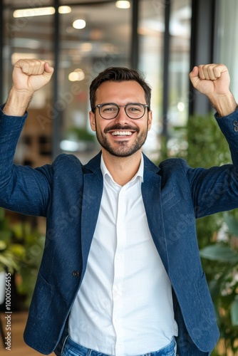 Man celebrating in a modern office, showcasing success and happiness with rai...