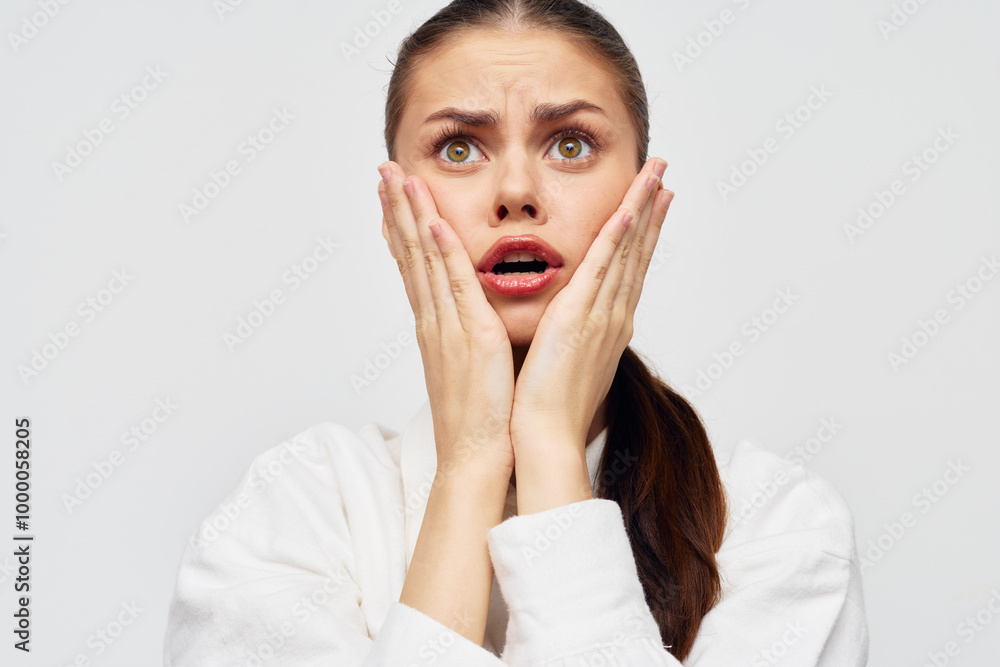 Woman expressing shock and concern with hands on her face, showcasing a range of emotions in a minimalistic setting Bright, neutral background enhances the subject s expression Woman expressing shock and concern with hands on her face, showcasing a range of emotions in a minimalistic setting Bright, neutral background enhances the subject s expression