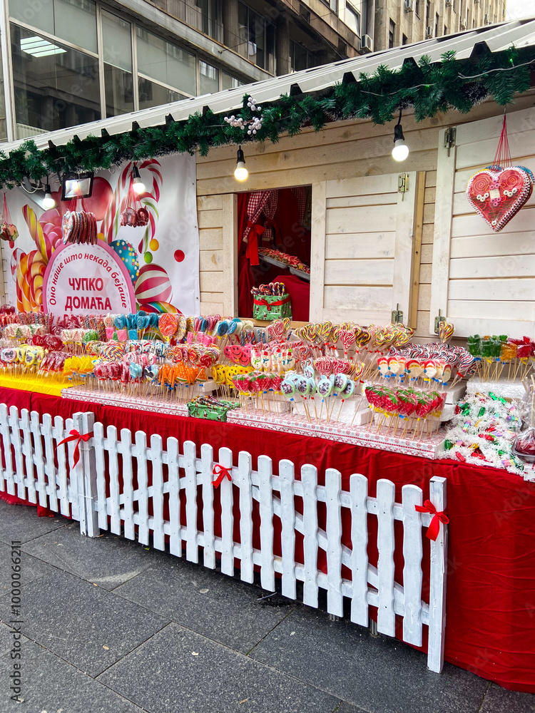 Naklejka premium Colorful heart-shaped cookies hang elegantly on display at a festive Christmas market stall. Vibrant array of sweets. Inviting and cheerful atmosphere winter holidays.