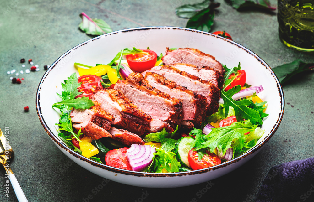 Foodie food salad with grilled duck and vegetables, lettuce and arugula on green background, top view Foodie food salad with grilled duck and vegetables, lettuce and arugula on green background, top view
