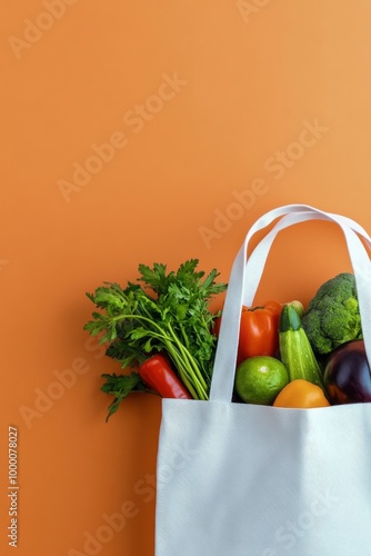 Fresh vegetables and herbs in a reusable bag against a vibrant orange background