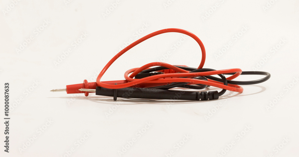 Red and black test leads tangled on plain white background, ideal for electronics and repair themes. Red and black test leads tangled on plain white background, ideal for electronics and repair themes.