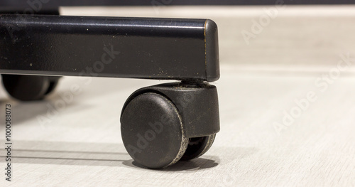 Close up of black office chair caster wheel on light colored floor. photo