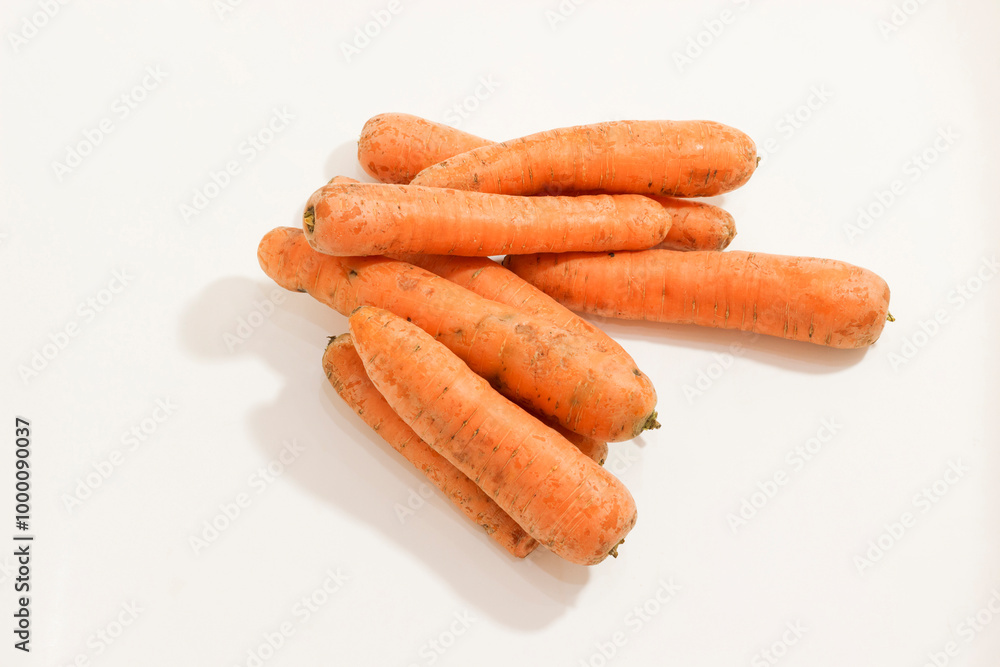 A pile of fresh, unwashed carrots with rustic appearance on white background, showcasing their natural texture. A pile of fresh, unwashed carrots with rustic appearance on white background, showcasing their natural texture.