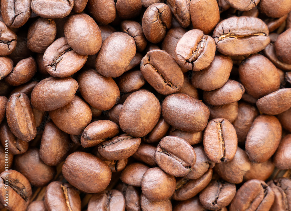 Naklejka premium Fragrant roasted Arabica coffee beans in close-up. The background is dark brown from coffee beans
