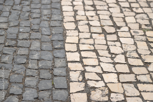 Abstract background of cobblestone pavement in two colors, gray and white, handmade Portuguese sidewalk. Costa Nova, Aveiro, Portugal.