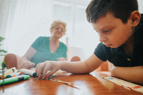 An engaging scene of a young boy playing a pick-up sticks game with his grandmother in a cozy living room, capturing the warmth and bonding of family time. photo