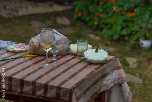 Garden chair in the rain. On the table is a glass of wine and patizon - Cucurbita pepo var. patissoniana