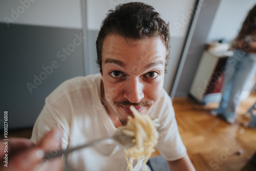 Bilde på lerret A man in a white shirt looks happy as he eats spaghetti at home