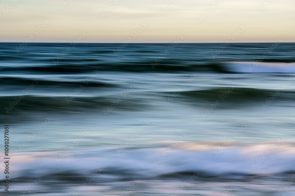 Obraz premium Soft, flowing ocean waves captured in a blur during sunset.
