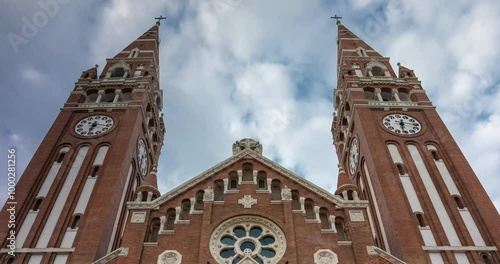 Szeged, Hungary - July 20, 2024: The Votive Church and Cathedral of Our Lady of Hungary. Time-lapse, zoom-out transition. Sunny day, medium cloudy sky. photo