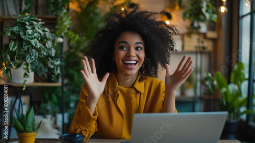 A joyful young woman with Blasian and African American heritage is actively engaged in a virtual video call from her home office. Her enthusiastic demeanor highlights the collabora photo