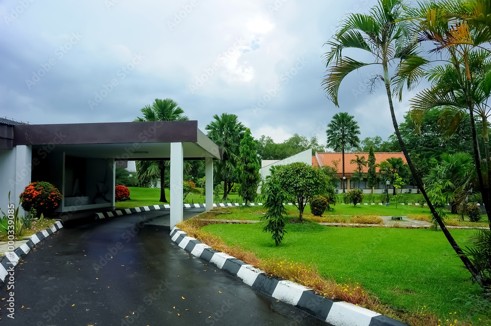 A serene villa surrounded by lush greenery, featuring a traditional yet modern architectural design with a sloping red-tiled roof. The villa is nestled amidst a garden landscape A serene villa surrounded by lush greenery, featuring a traditional yet modern architectural design with a sloping red-tiled roof. The villa is nestled amidst a garden landscape