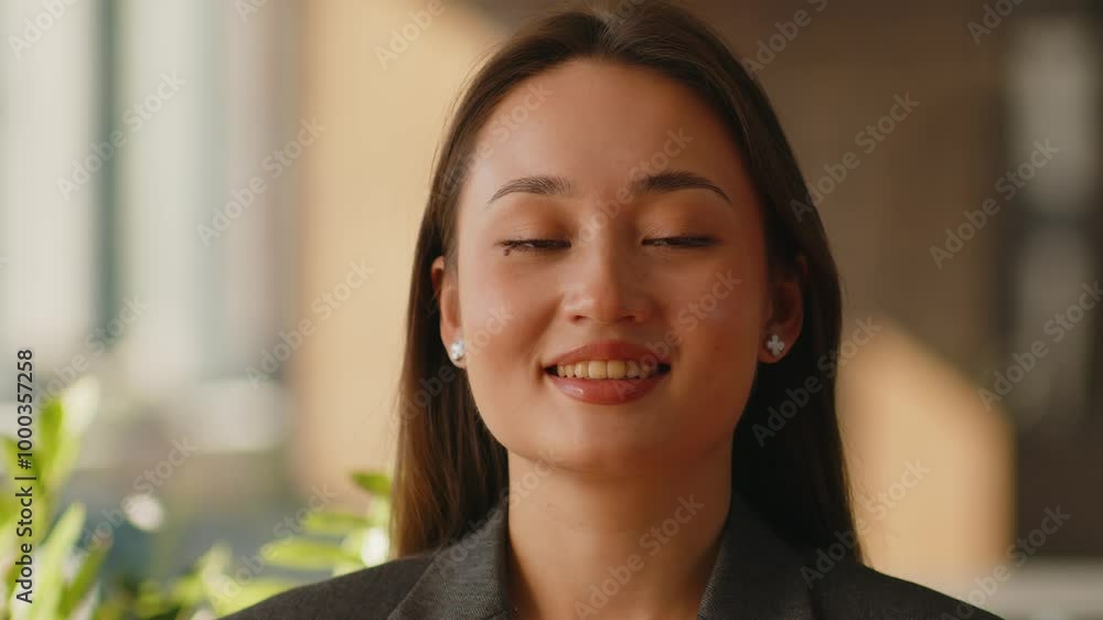 Close up. Portrait of a young smiling businesswoman standing in a modern office. Stylish happy asian female employee in a suit looks at the camera. Close up. Portrait of a young smiling businesswoman standing in a modern office. Stylish happy asian female employee in a suit looks at the camera.