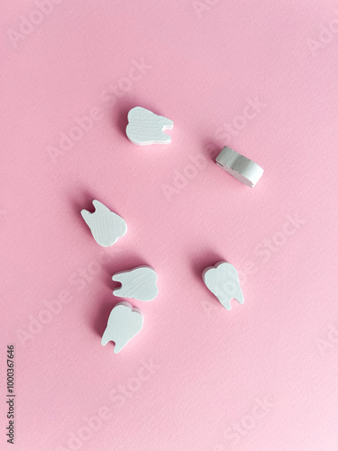 White wooden teeth on a pink background. Dental health concept. Dentist day concept. Top view, space for copy text