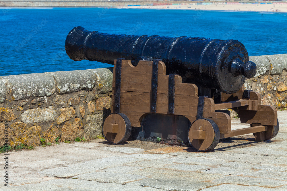 A historic cannon mounted on a stone fort wall overlooking the ocean A historic cannon mounted on a stone fort wall overlooking the ocean