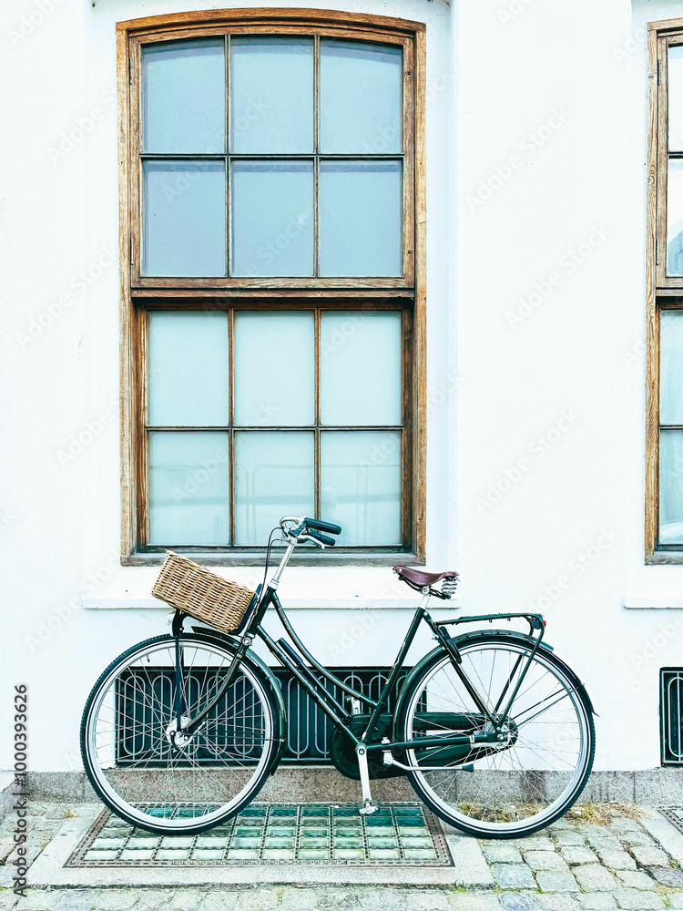 Bicycle leaning against the wall of a building with windows Bicycle leaning against the wall of a building with windows