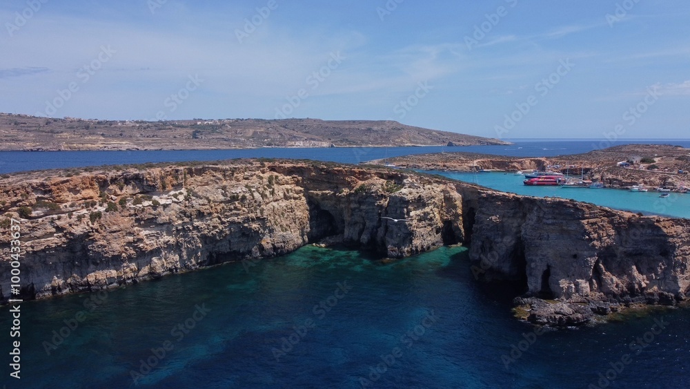 Aerial view of the sea caves of Cominotto uninhabited island near Comino, Maltese islands. Seagull flying in the frame. High quality photo Aerial view of the sea caves of Cominotto uninhabited island near Comino, Maltese islands. Seagull flying in the frame. High quality photo