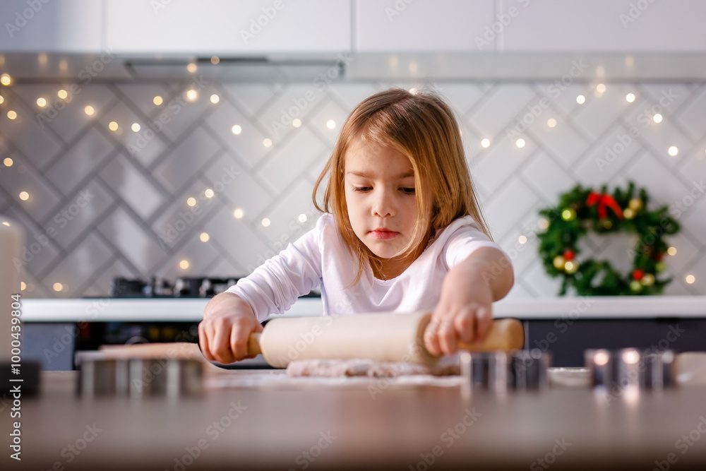 A girl is rolling out dough for gingerbread cookies in the kitchen, embracing the Christmas spirit A girl is rolling out dough for gingerbread cookies in the kitchen, embracing the Christmas spirit