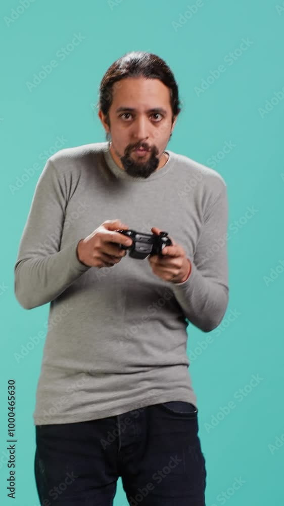 Vertical video Portrait of man playing videogames holding controller, isolated over studio background. Gamer focused on gaming, participating in PvP online multiplayer game using console system Vertical video Portrait of man playing videogames holding controller, isolated over studio background. Gamer focused on gaming, participating in PvP online multiplayer game using console system