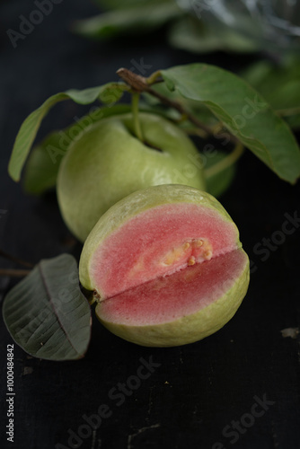 Pink and green guava slice with leaf on dark table