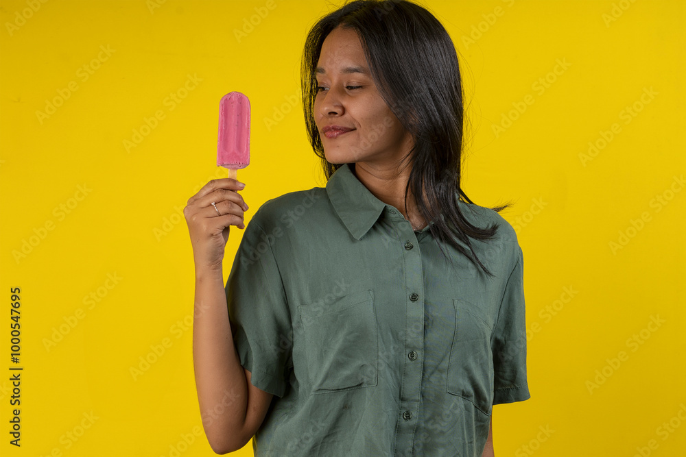 Young woman in studio photo with a strawberry popsicle in her hand Young woman in studio photo with a strawberry popsicle in her hand