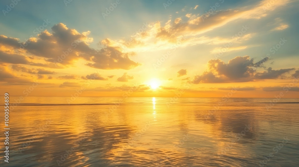 Fototapeta premium Golden sky at sunrise with soft clouds and reflections on the ocean, creating a serene and picturesque scene
