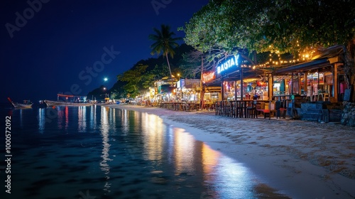 A night view of the bustling beach bars along Sairee Beach, Koh Tao, with twinkling lights reflecting on the calm water.