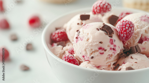 A bowl of creamy raspberry ice cream topped with fresh raspberries and chocolate chunks, creating a delightful and refreshing dessert treat.