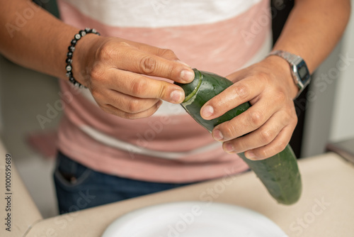 Billede på lærred close up on hands of a young man rubbing cucumber ends to reduce bitterness; His